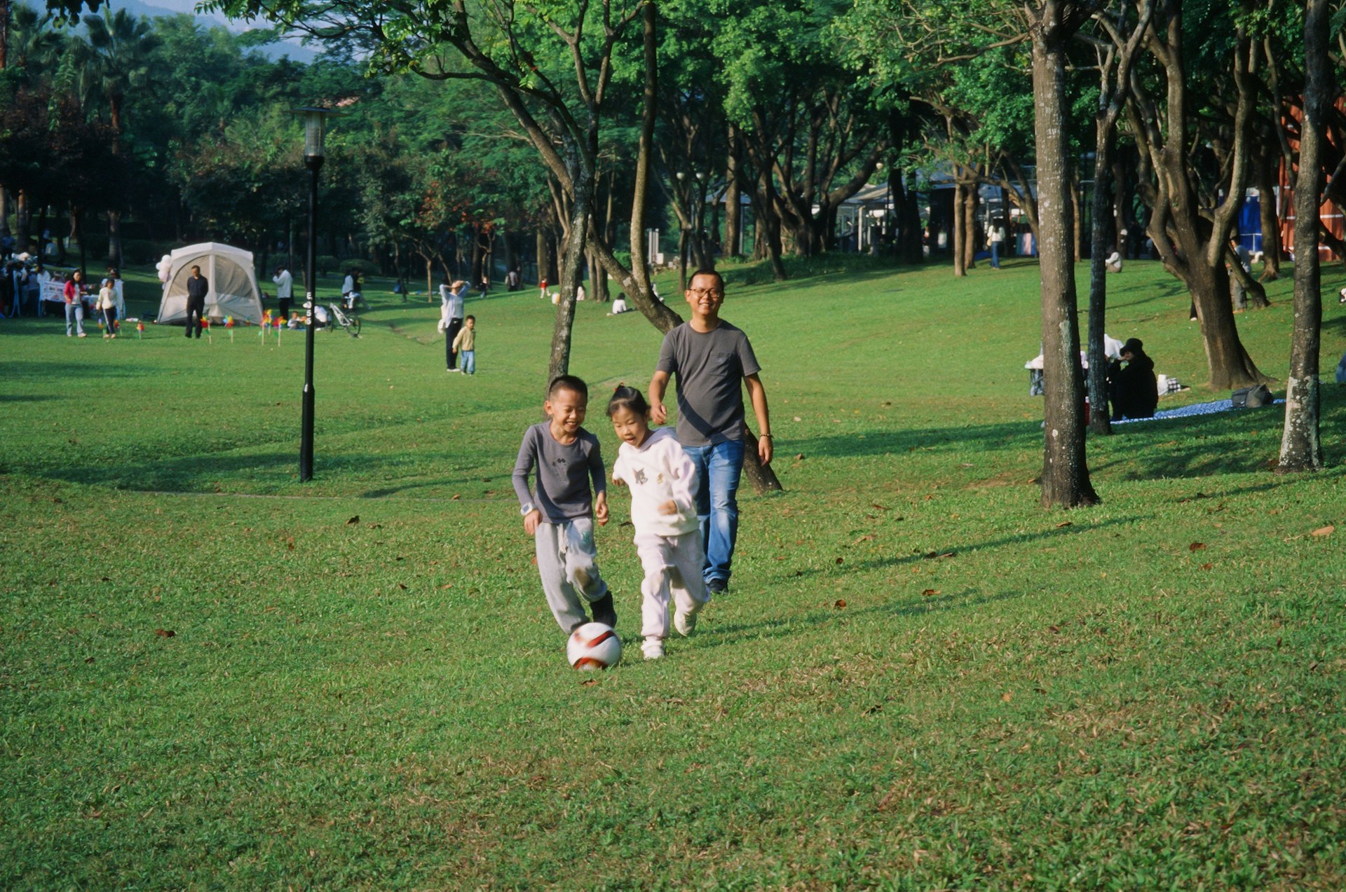 A group of people walking across a lush green park
